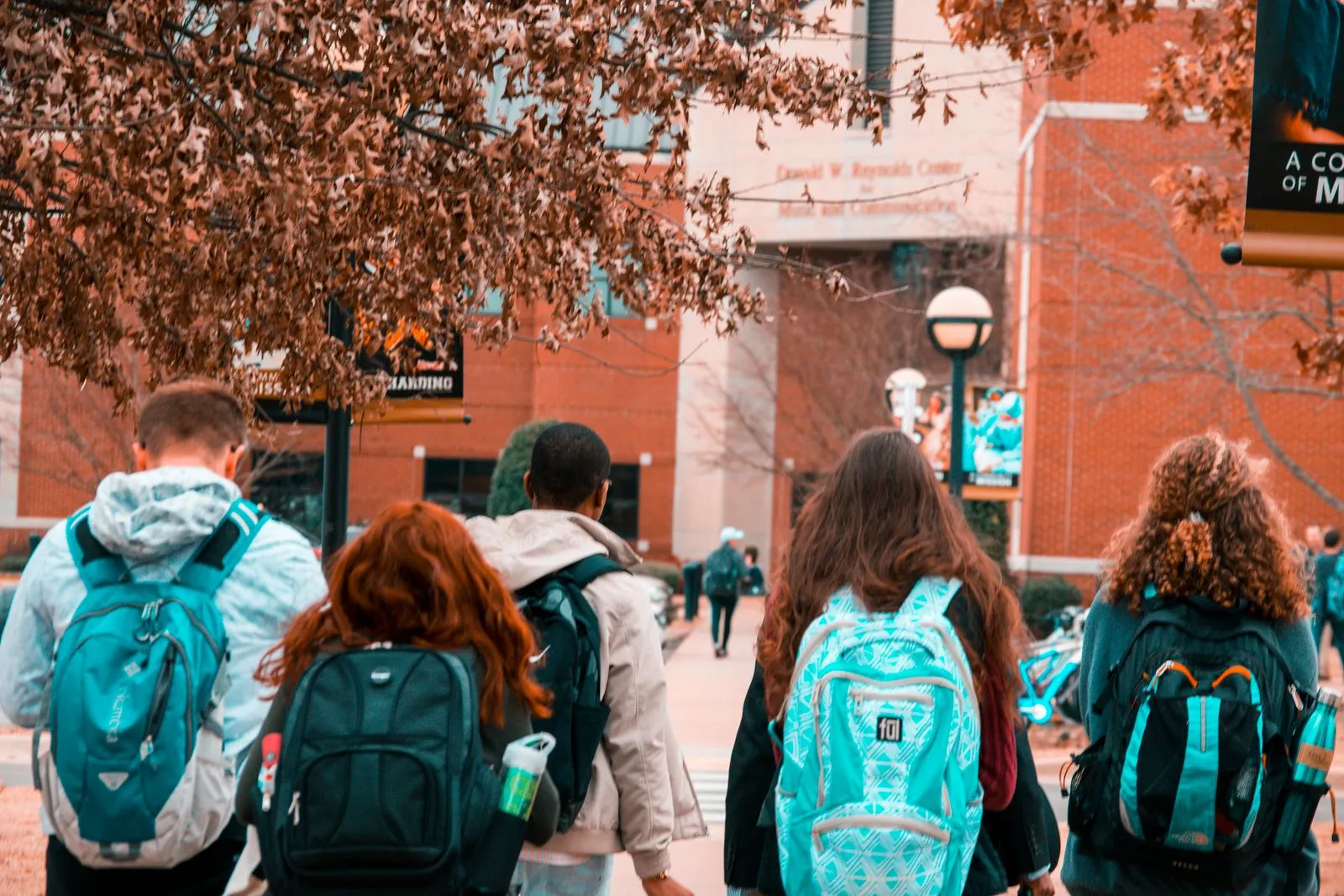 Group of college students with backpacks walking together outdoors on a campus pathway